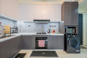 Eine moderne Küche mit grauen Schränken, einem eingebauten Backofen, einer Mikrowelle und einer Waschmaschine.