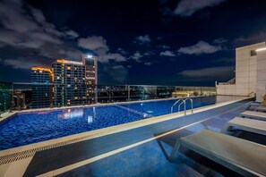 A rooftop swimming pool with lounge chairs and a view of city buildings at night. - Central location. Big comfort. Your stay just got a little more fun. (Nairobi)