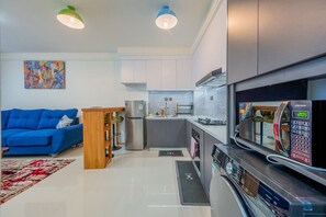 A modern kitchen with a microwave, refrigerator, and sink. - Central location. Big comfort. Your stay just got a little more fun. (Nairobi)