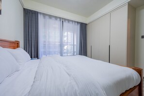 A hotel room with a large bed, a wardrobe, and a window with curtains. - Central location. Big comfort. Your stay just got a little more fun. (Nairobi)