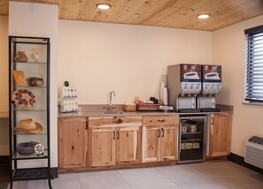 Eine moderne Küche mit Holdekor-Schränken, einer integrierten Kaffeemaschine und einer Glastheke mit Dekoration.