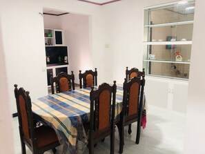 A dining area with a table set for six, surrounded by wooden chairs with cushioned seats. - Chathu Villa Bentota (Bentota)