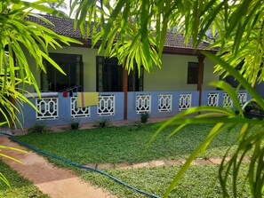 A residential building with a tiled roof, a blue exterior wall with decorative white window frames, and a well-maintained lawn. - Chathu Villa Bentota (Bentota)