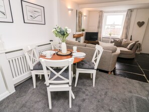 A modern living room with a dining area, a sofa set, a flat-screen TV, and artwork on the walls. - Crag Cottage (Settle)