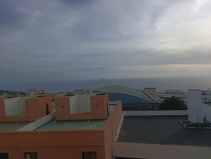 Tagter med bygninger i baggrunden, klar himmel og et fjernt havudsigt.