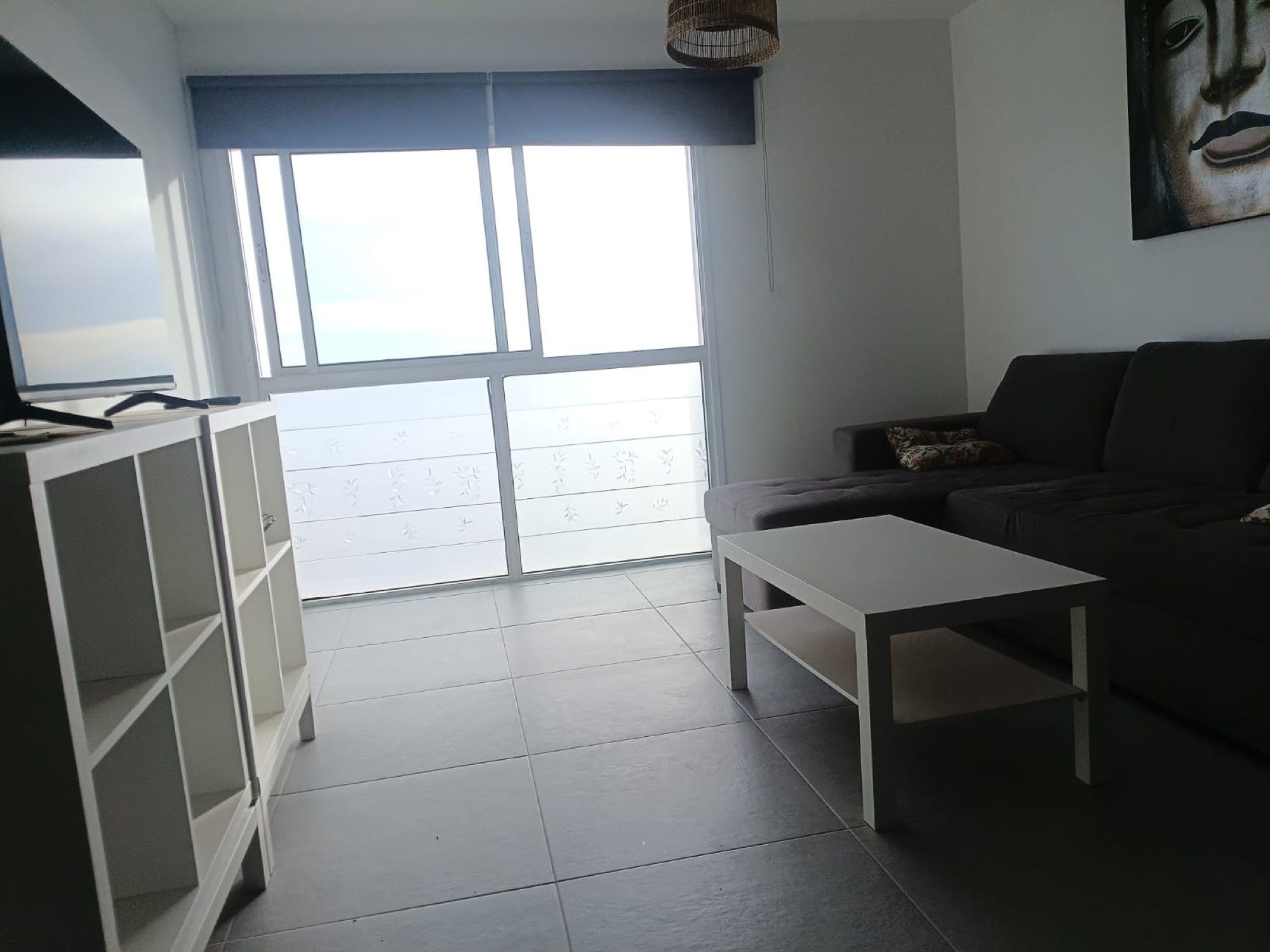 Una sala de estar con un sofá, una mesita de centro y un televisor sobre un mueble.