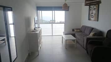 Una sala de estar moderna con un sofá, una mesa de centro y un televisor sobre un mueble.