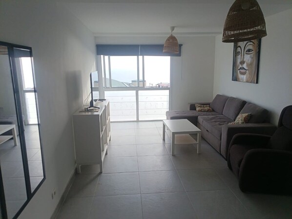 A modern living room with a sofa, a coffee table, and a TV on a stand.