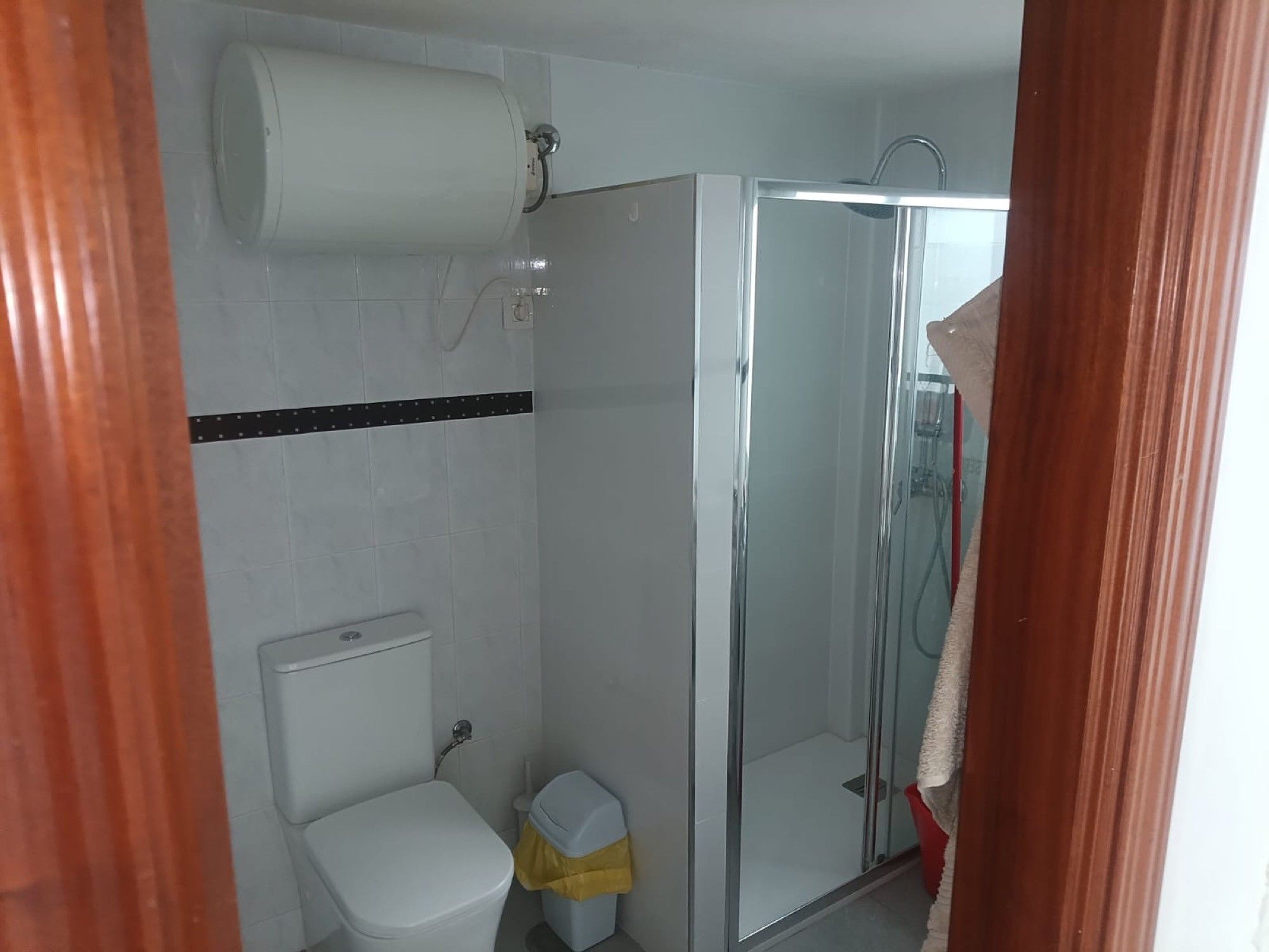 Un baño con inodoro, cabina de ducha y soporte para papel higiénico.