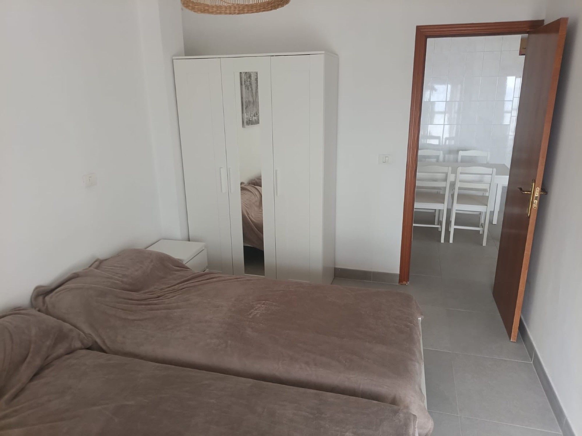Un dormitorio con cama, armario y puerta que da a un comedor.