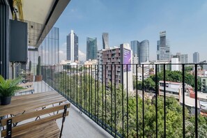 Ein Balkon mit Blick auf eine Stadtlandschaft, darunter moderne Gebäude und ein klarer Himmel.