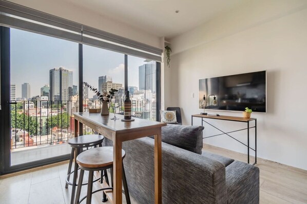 Ein modernes Wohnzimmer mit Blick auf die Stadt, einem Essbereich und einem Flachbildfernseher.