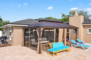 A covered outdoor seating area with a gazebo, lounge chairs, and a barbecue grill. - Spectacular renovated 3-bedroom house in Jax Beach with pool patio & yar (Jacksonville Beach)