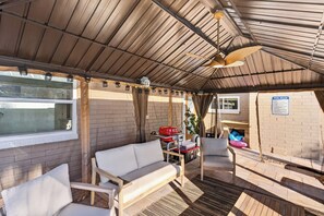 Un espace extérieur aménagé, abrité et doté d’un canapé, de chaises et d’une table.