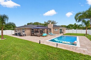 A backyard with a swimming pool, patio furniture, and a covered seating area. - Spectacular renovated 3-bedroom house in Jax Beach with pool patio & yar (Jacksonville Beach)