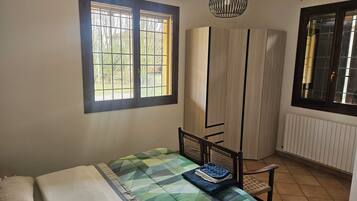Una camera da letto con un letto, una sedia, un armadio e due finestre.