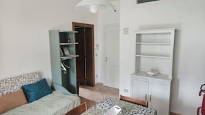 A room with a bed, a table with a patterned tablecloth, a bookshelf, and a wardrobe. - The Lune Annex - Two Connecting Apartments (Emilia-Romagna)