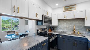 A modern kitchen with white cabinets, a built-in microwave, a gas stove, and a granite countertop. - Amazing location at Indian Springs Colony 30-day minimum stay (Largo)