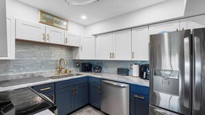 Une cuisine moderne dotée d’appareils électroménagers en acier inoxydable, de meubles bleus et d’un plan de travail en granit.
