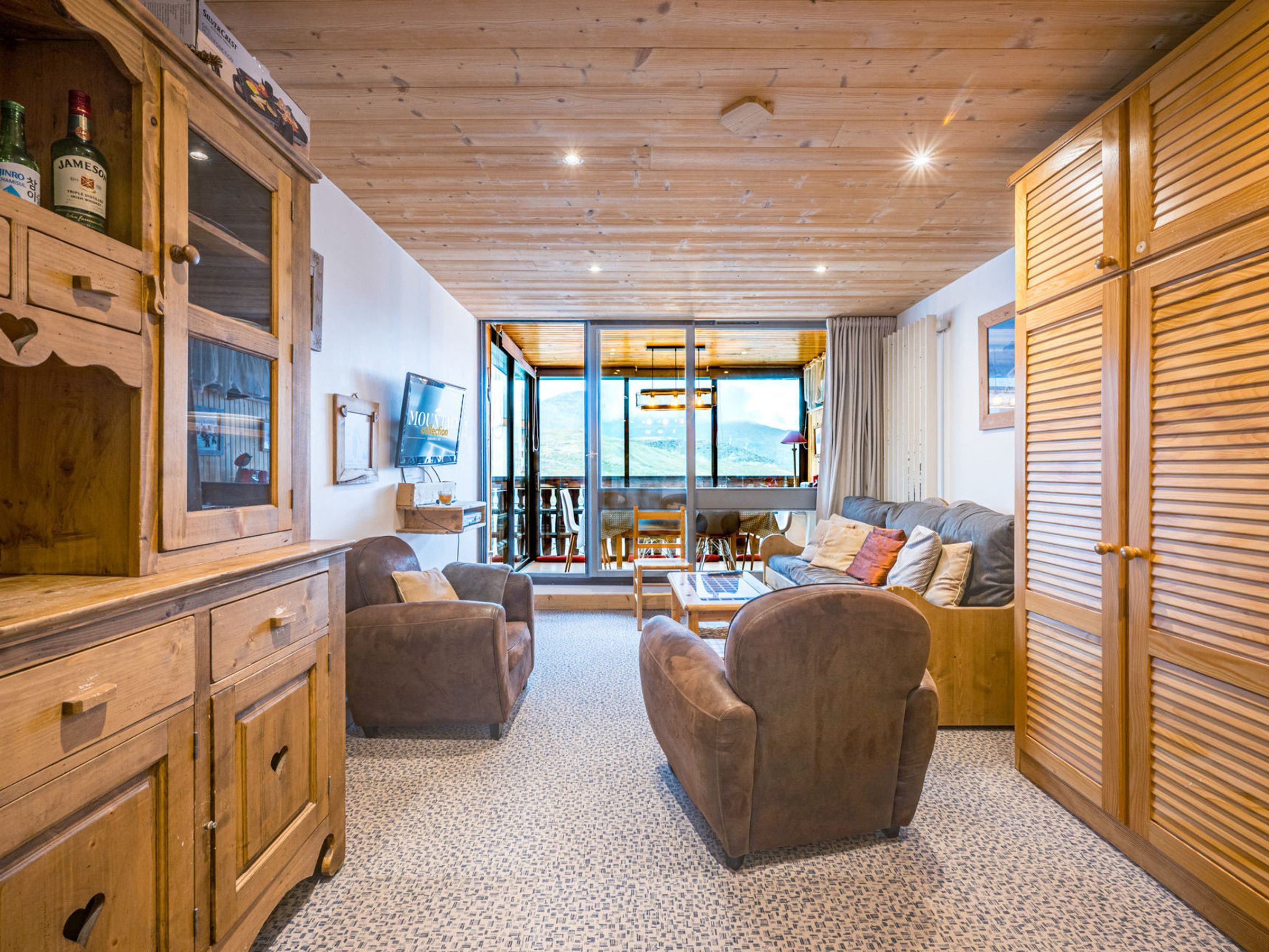 A cozy living room with a fireplace, wooden furniture, and a view of the outdoors.