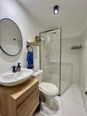Ein modernes Badezimmer mit Waschbecken, Toilette und Duschkabine aus Glas.