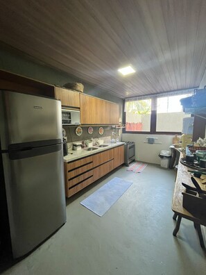 A compact kitchen with a refrigerator, wooden cabinets, a sink, and a window. - House with 3 bedrooms and swimming pool, 7 min walk from Riacho Beach – Milagres/AL (Unknown)