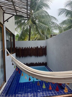 A pool area with a hammock, blue tiled floor, and a wall with vertical wooden slats. - House with 3 bedrooms and swimming pool, 7 min walk from Riacho Beach – Milagres/AL (Unknown)