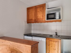 A kitchen with wooden cabinets, a microwave, a dishwasher, and a granite countertop. - Bright apartment near slopes - 6 guests (Villarodin-Bourget)