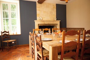 A dining room with a brick fireplace, wooden chairs, and a table set for a meal. - L'Aposée, a country house in Normandy, where nature meets creative experiences (Thury-Harcourt-le-Hom)