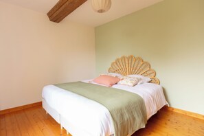 Quarto com cama, piso de madeira e parede clara e simples.