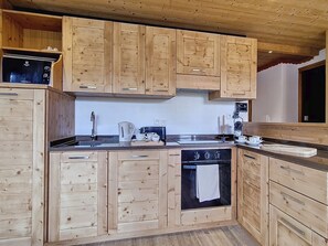 Eine Küche mit Holzschränken, einem Herd, einer Spüle und einer Kaffeemaschine.