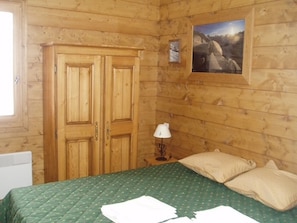 Une pièce en bois avec un lit, une armoire, une lampe et un tableau encadré accroché au mur.