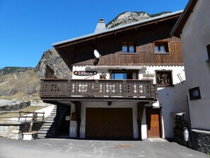 A traditional chalet with a wooden facade, a balcony with decorative elements, and a mountain backdrop. - Cozy apartment in the center - 6 guests (Pralognan-la-Vanoise)