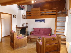 A cozy room with a wooden bunk bed, a sofa, a fireplace, and a framed picture on the wall. - Cozy apartment in the center - 6 guests (Pralognan-la-Vanoise)