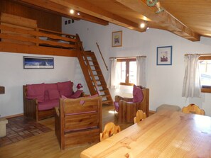 A wooden interior with a sofa, dining table, and chairs. A wooden ladder is leaning against the wall. - Cozy apartment in the center - 6 guests (Pralognan-la-Vanoise)