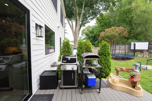 Eine Terrasse mit Grill, Pizzaofen und Kinderspielbereich.