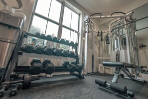 A gym with dumbbells, weight machines, and a window. - Modern 6 Bedroom Northern VA/DC Dream Home! +Gym + Pool + Theater + Playroom (McLean)