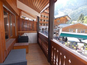 A wooden balcony with a view of a mountain and a restaurant below. - Apartment in the heart of the resort - 6 guests (Pralognan-la-Vanoise)