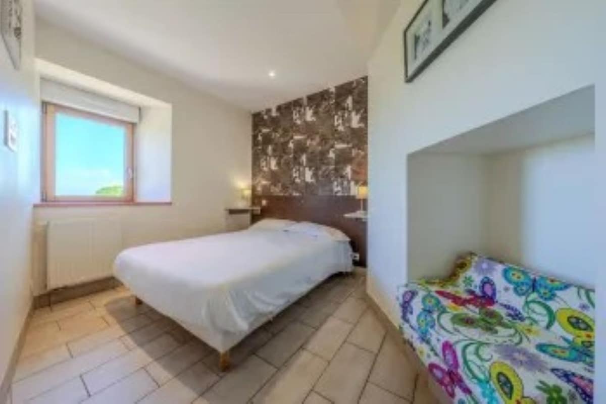 Un dormitorio pequeño con una cama individual, un ventanal y una decoración de pared colorida.