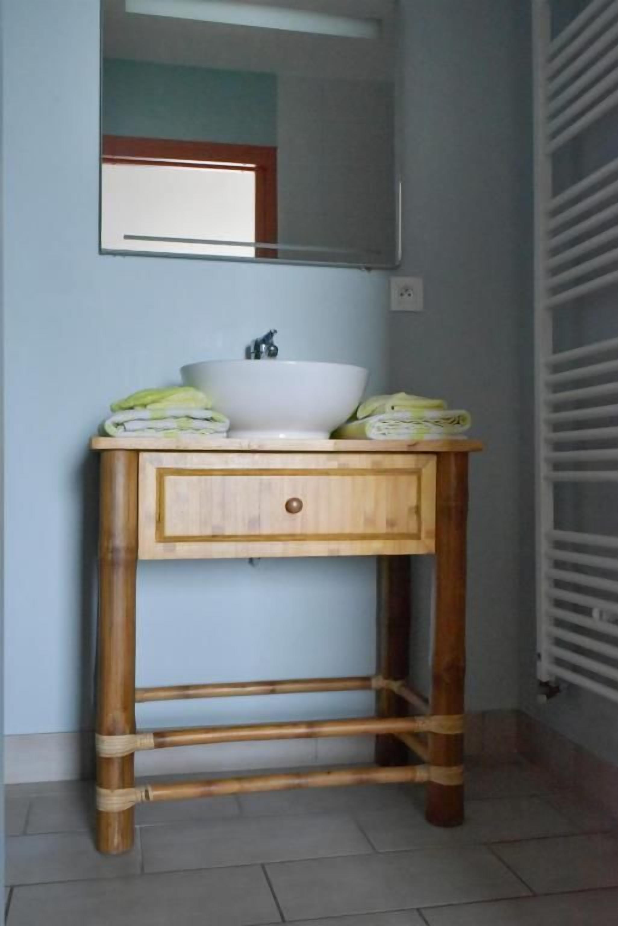A bathroom with a wooden vanity, a white sink, and a mirror above it.