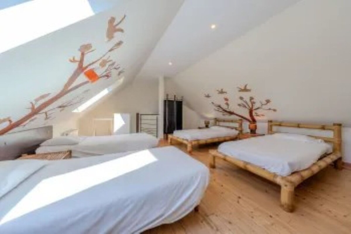 Un dormitorio con dos camas, suelo de madera y techo inclinado con tragaluz.