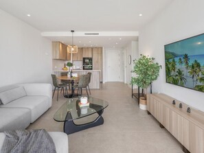 A modern living room with a glass coffee table, a sofa, and a dining area with chairs and a small table. - Seaside residence, pets welcome (Estepona)