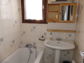 Un baño con bañera, lavamanos y espejo sobre el lavamanos.