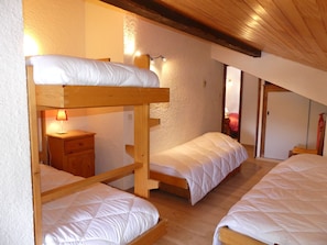 A dormitory room with bunk beds, a bedside table with a lamp, and a wooden ceiling. - Duplex close to Nordic area - 6 guests (Pralognan-la-Vanoise)
