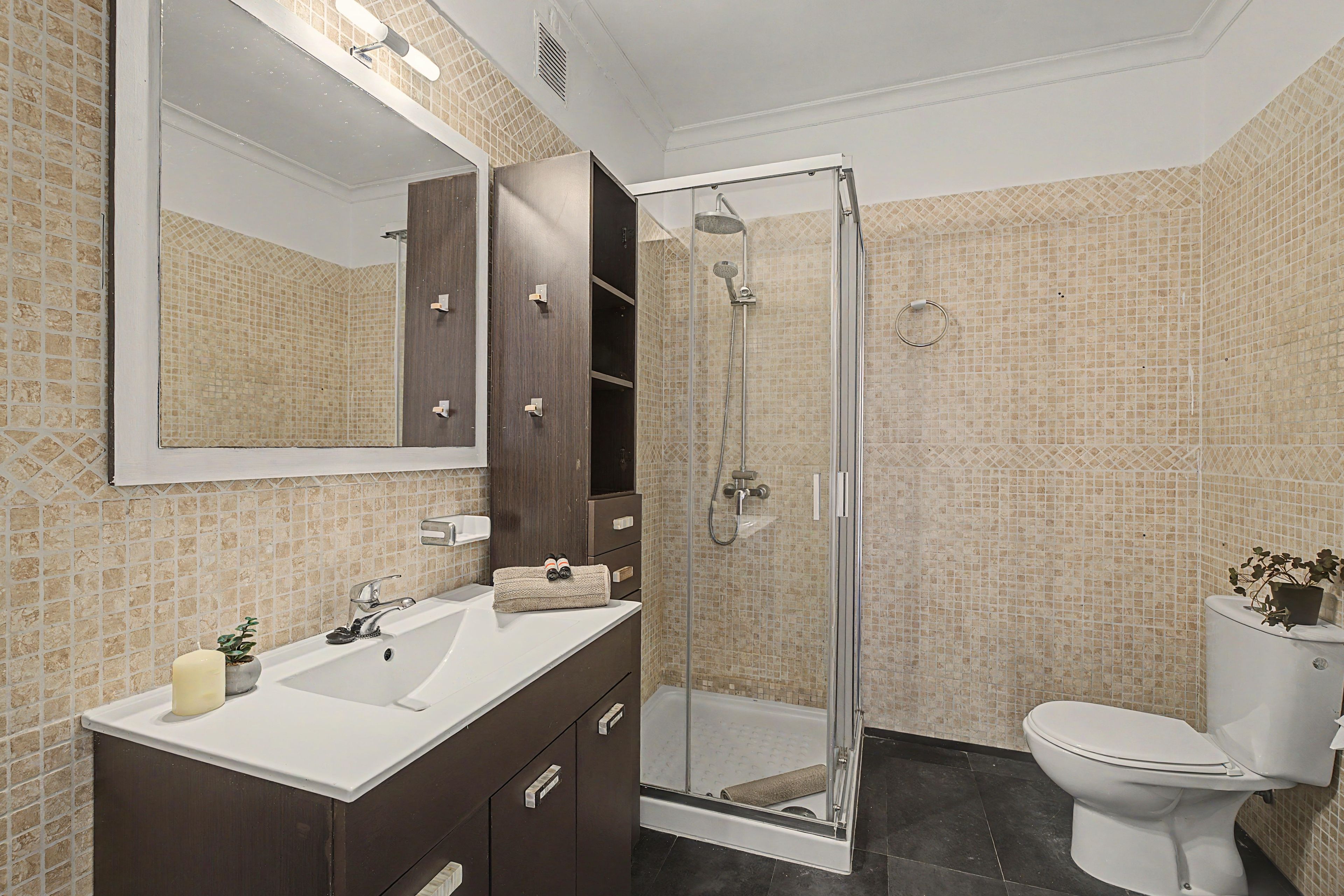 Un baño con ducha, inodoro, lavabo y espejo.