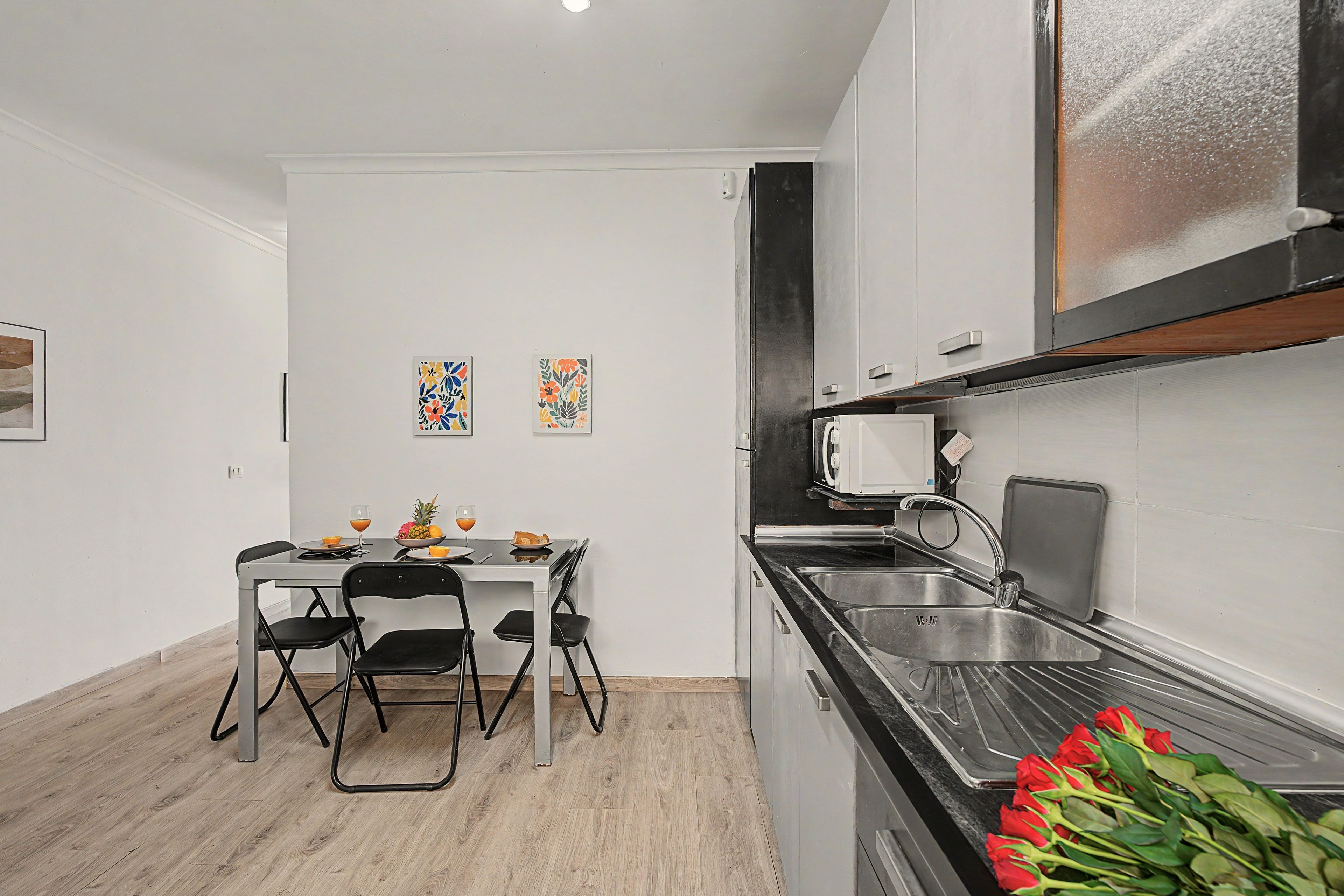 Una cocina compacta con una mesa, sillas y un lavamanos.