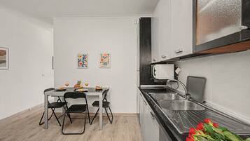 Una cocina compacta con una mesa, sillas y un lavamanos.