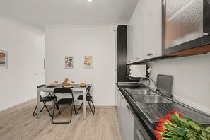 Una cocina compacta con una mesa, sillas y un lavamanos.