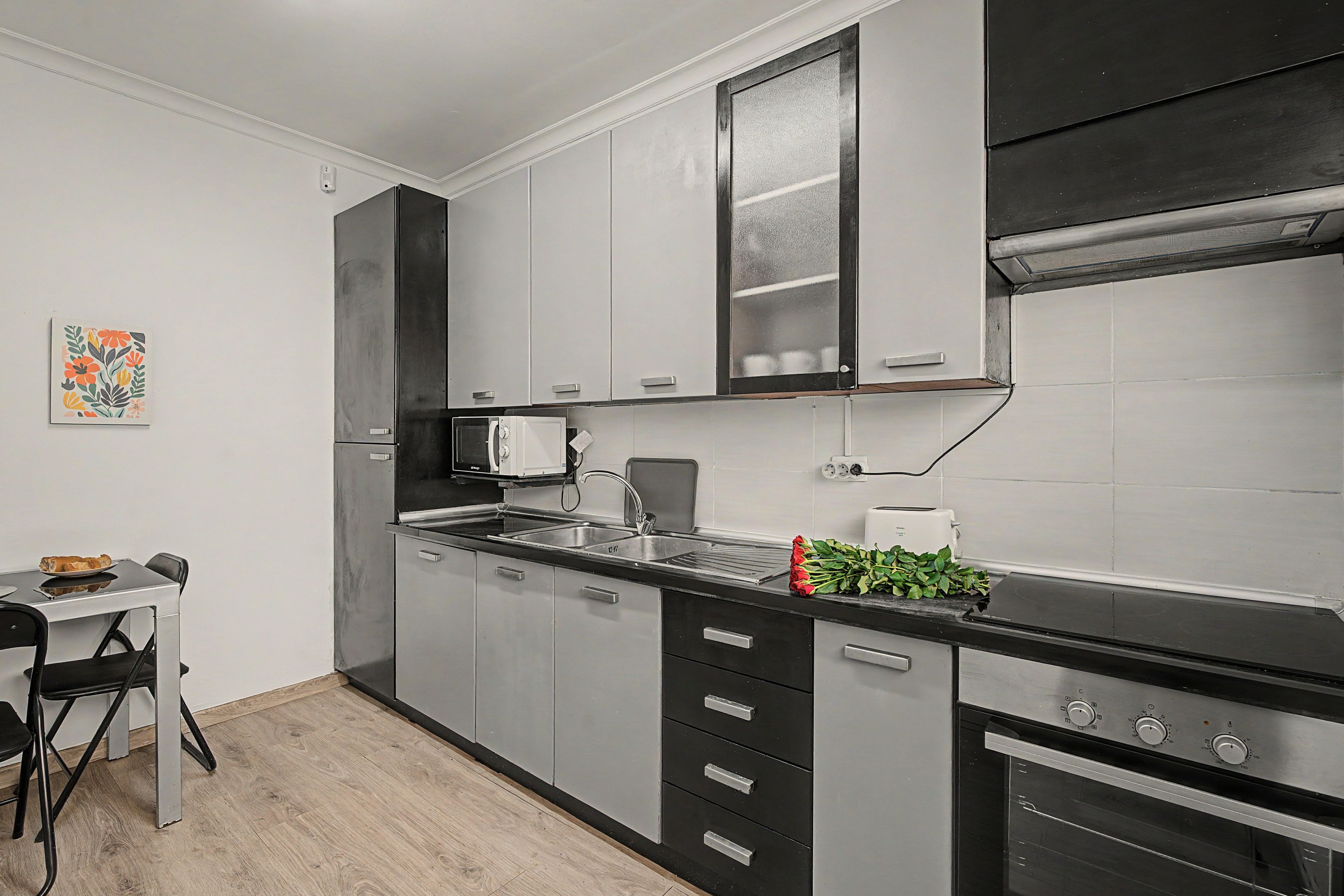 Una cocina moderna con electrodomésticos de acero inoxidable, una encimera negra y un comedor con mesa y sillas.