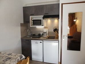 Cozinha compacta com micro-ondas, cafeteira e lava-louças.